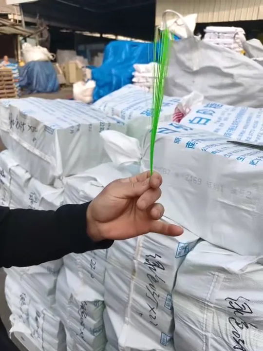 Worker bend-testing green PET broom filament to check its elasticity